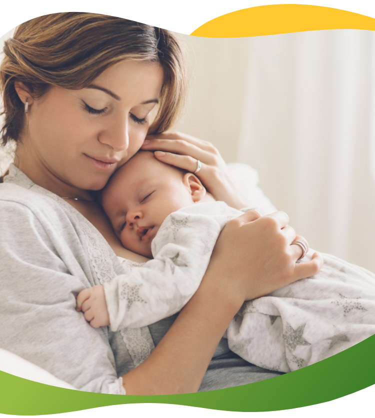 Jauna motina užmerktomis akimis glaudžia prie krūtinės miegantį kūdikį