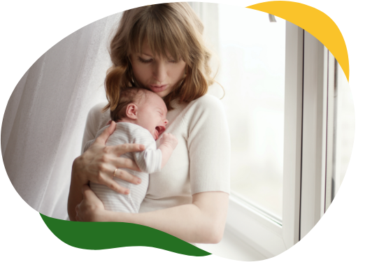 Jauna motina glaudžia prie krūtinės verkiantį kūdikį, kad palengvintų dieglius